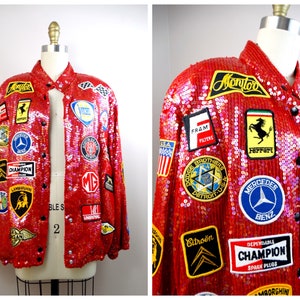 May include: A red sequined jacket adorned with various patches, including Ferrari, Mercedes-Benz, and Champion. The jacket features a classic bomber style with a button-up front and a collar. The patches showcase automotive and racing-themed logos.