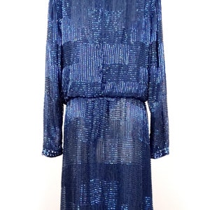 May include: A long-sleeved, navy blue sequined dress with a geometric pattern. The dress has a fitted bodice and a flowing skirt.