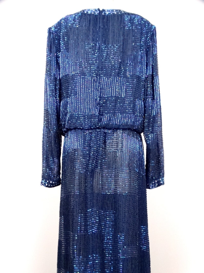 May include: A long-sleeved, navy blue sequined dress with a geometric pattern. The dress has a fitted bodice and a flowing skirt.