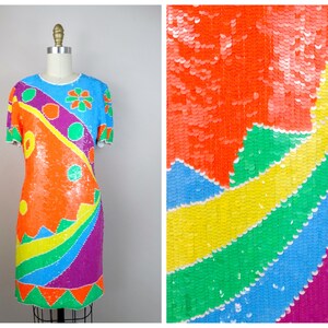 May include: A short-sleeved sequined dress with a rainbow pattern. The dress is made of colorful sequins and has a geometric design.