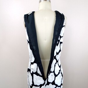 May include: A black and white sequined dress with a low back and a V-neckline.
