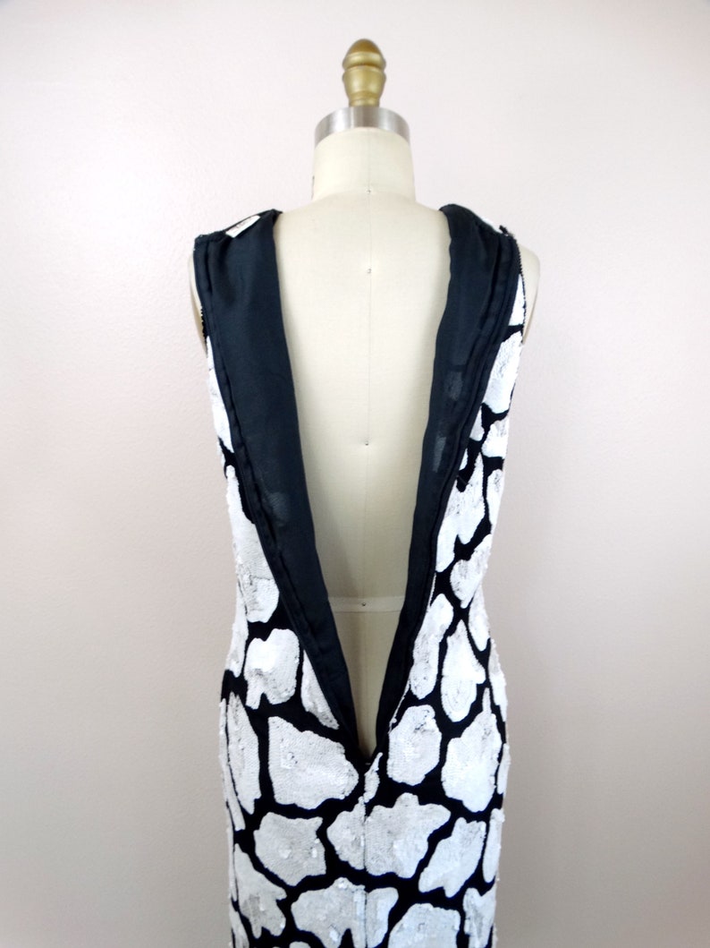 May include: A black and white sequined dress with a low back and a V-neckline.