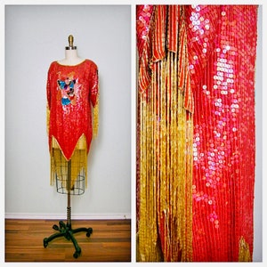 Puede incluir: Un vestido rojo de lentejuelas con flecos dorados y un diseño bordado de colores. El vestido está en un maniquí y tiene un corpiño ajustado y una falda fluida.