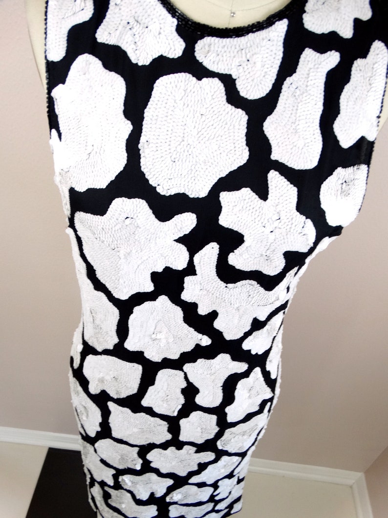May include: A sleeveless black and white dress with a sequined animal print pattern.