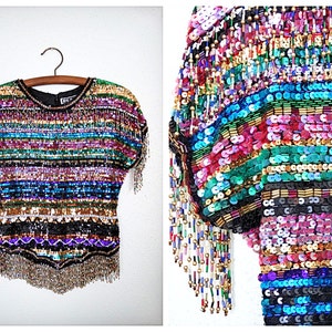 May include: A multi-colored sequined top with fringe. The top has a striped pattern with shades of blue, green, pink, purple, gold, and black.