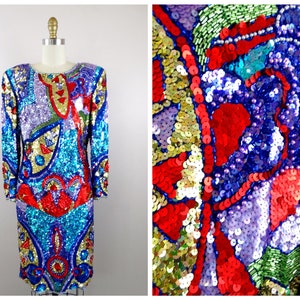 May include: A vibrant, multi-colored sequined dress with a geometric pattern. The dress features shades of blue, red, purple, green, and gold. The sequins are arranged in a mosaic-like design, creating a dazzling effect.