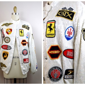 May include: White sequined jacket with various car brand patches, including Ferrari, Maserati, Lamborghini, and Porsche.