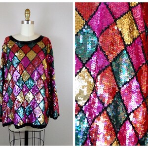 May include: A colorful sequined sweater with a diamond pattern in shades of pink, red, gold, green, and blue.