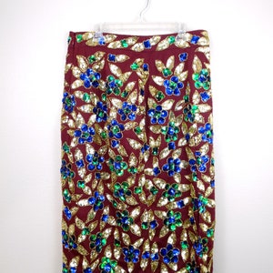 Puede incluir: Una falda color burdeos con un estampado floral hecho de lentejuelas doradas, azules y verdes.