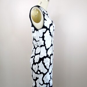 May include: A sleeveless black and white dress with a unique, abstract pattern. The dress is made of a textured fabric and has a fitted silhouette.