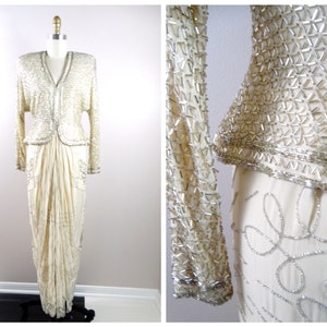 May include: A white beaded evening gown with a long skirt and a fitted bodice. The gown is embellished with silver beads and sequins.