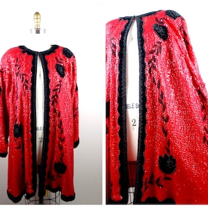 May include: A red sequined jacket with black floral embroidery and a black trim. The jacket is open in the front and has a long, flowing silhouette.
