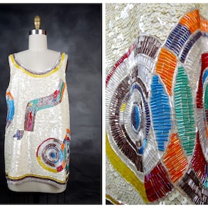 May include: A white sleeveless top with a colorful geometric pattern made of sequins and beads. The pattern includes circles, lines, and swirls in shades of blue, green, red, orange, and yellow.