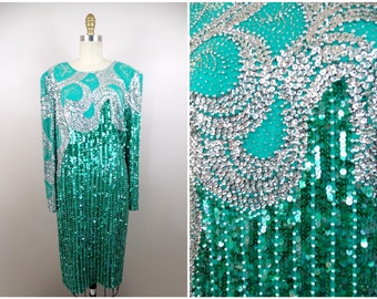 May include: A teal sequined dress with silver sequins forming a design on the bodice. The dress has long sleeves and a fitted silhouette.