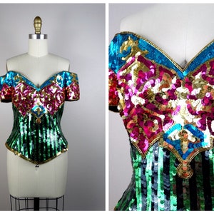 May include: A sequined off-the-shoulder top with a green, blue, pink and gold design. The top has a sweetheart neckline and short sleeves.