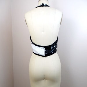 May include: A black and white halter top with sequins. The top is on a white dress form.