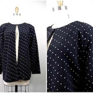 Peut inclure: Un cardigan noir à devant ouvert avec des pois blancs. Le cardigan est sur un mannequin blanc.