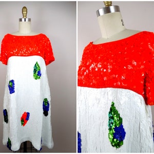 Puede incluir: Un vestido blanco de lentejuelas con un top rojo de lentejuelas y detalles de lentejuelas verdes, azules y rojas.