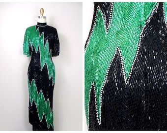 May include: A black and green sequined dress with a zig-zag pattern. The dress has a high neck and short sleeves.