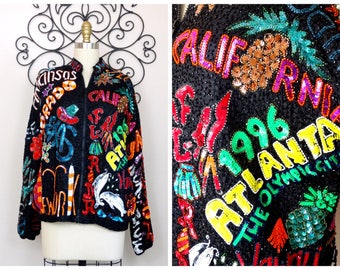May include: A black sequined jacket with a zip fastening. The jacket is covered in colourful sequins and embroidery, featuring the words "California", "Atlanta 1996", and "The Olympic City".