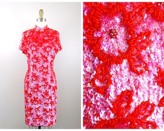 May include: A red and pink sequined dress with a mandarin collar and short sleeves. The dress is fully covered in sequins that form a floral pattern.