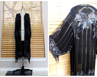May include: A long black beaded and sequined kimono with fringe. The kimono has a large iridescent floral design on the back.