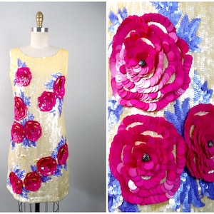Peut inclure: Une robe sans manches avec un fond jaune et des embellissements floraux roses et bleus. La robe est faite de paillettes et a une silhouette ajustée.