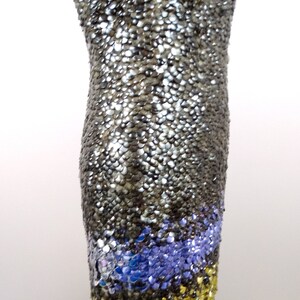May include: A silver sequined dress with a blue and gold sequined trim. The dress is on a mannequin.