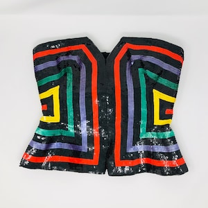 May include: A black strapless top with a geometric pattern of colourful stripes. The stripes are red, yellow, green, and purple.