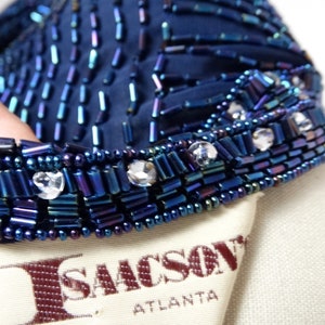 May include: A navy blue beaded top with iridescent beads and clear rhinestones. The top has a label that reads "I. Sacks, Atlanta".
