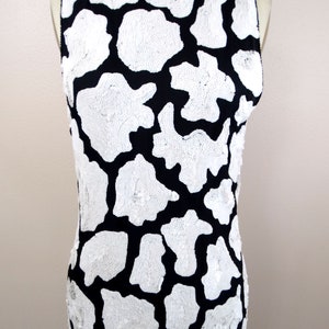 May include: A sleeveless black dress with a white sequined pattern. The pattern resembles animal print.