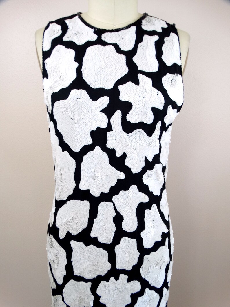 May include: A sleeveless black dress with a white sequined pattern. The pattern resembles animal print.