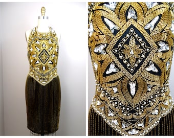 Può includere: Un abito nero con scollo halter con perline e paillettes dorate e argentate. L'abito presenta un motivo geometrico e un orlo a frangia.