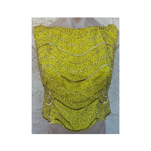 May include: A sleeveless, lime green top with a textured pattern and decorative, wavy lines. The top has a scoop neckline and is embellished with small, gold-colored beads. The garment is displayed on a mannequin.