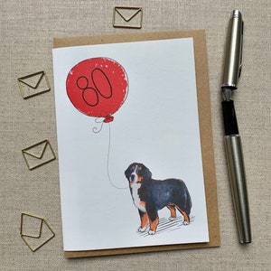 May include: A birthday card with a red balloon that says "80" and a Bernese Mountain Dog holding the string.