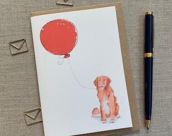 May include: A greeting card featuring a red balloon and a brown and white dog with its tongue out. The dog is holding the string of the balloon.