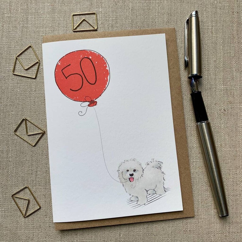 May include: A white card with a red balloon that says "50" on it. A white dog with black eyes is holding the string of the balloon.
