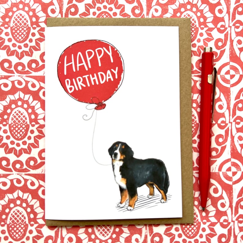 May include: A white card with a red balloon that says "Happy Birthday" and a black and white illustration of a Bernese Mountain Dog holding the balloon string.