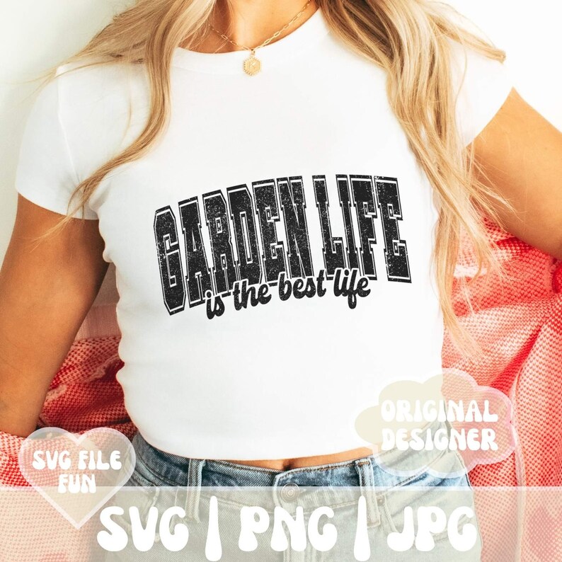 May include: A white t-shirt with black text that reads "GARDEN LIFE is the best life". The text has a distressed, vintage look. The shirt is being worn by a person with long blonde hair.