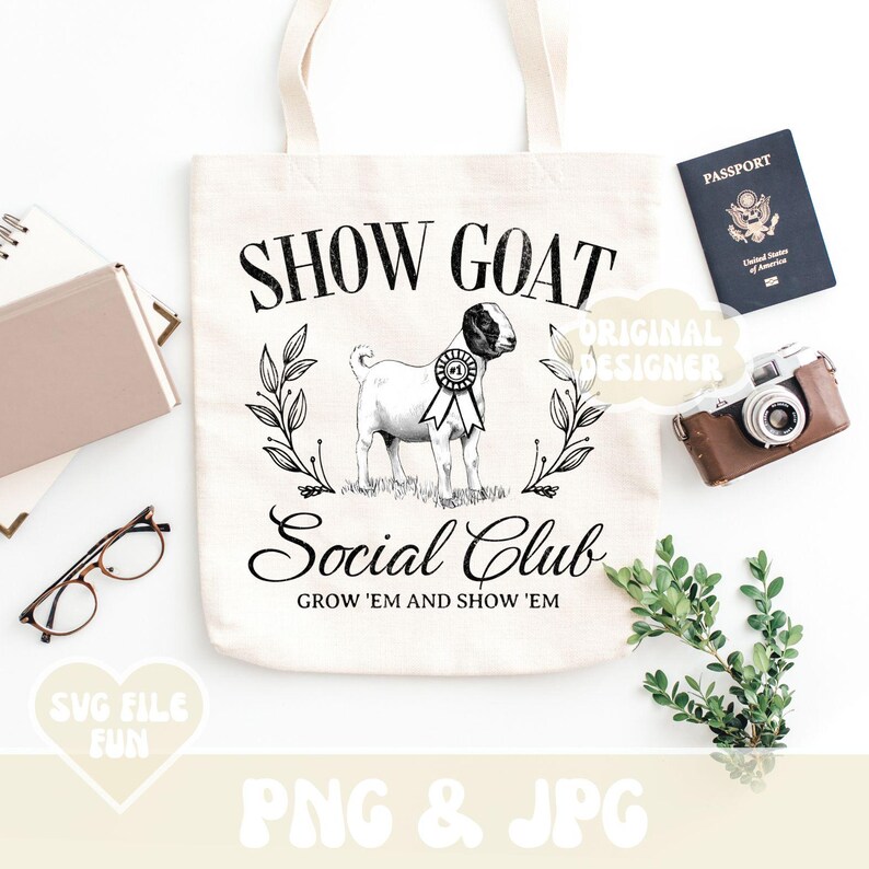 Puede incluir: Un bolso tote de color crema con el texto "SHOW GOAT Social Club" y un gr&aacute;fico de una cabra con una cinta. La imagen incluye un pasaporte, una c&aacute;mara vintage, gafas y un cuaderno. La frase "GROW 'EM AND SHOW 'EM" tambi&eacute;n est&aacute; impresa en el bolso.