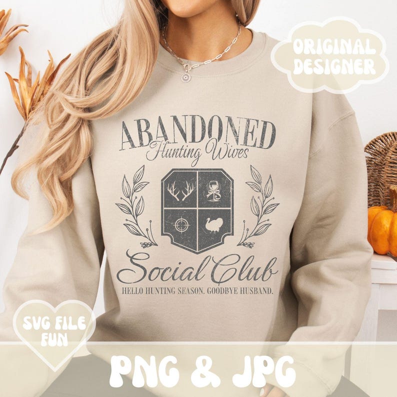 Może przedstawiać: Beżowa bluza z nadrukiem "ABANDONED Hunting Wives Social Club" i tekstem "HELLO HUNTING SEASON, GOODBYE HUSBAND."