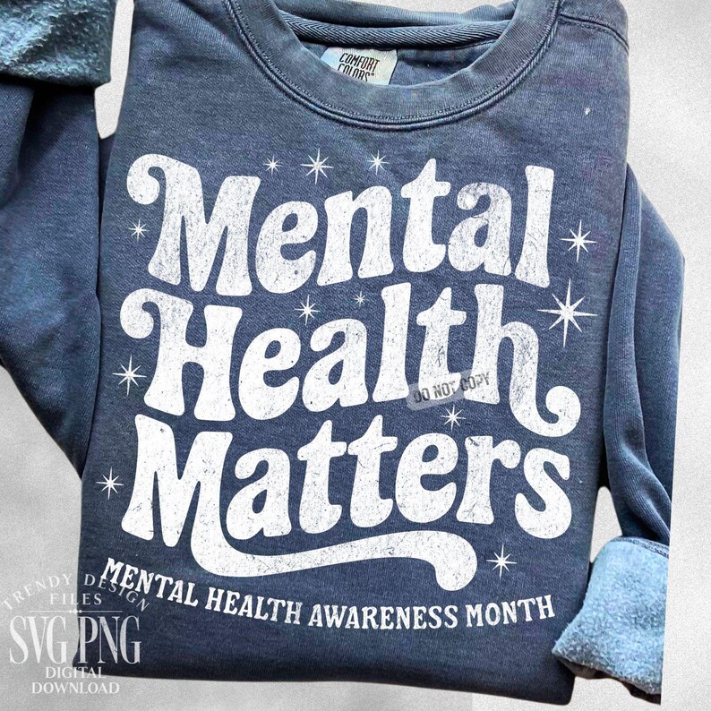 May include: A navy blue sweatshirt with the words "Mental Health Matters" in large, white, distressed lettering. The phrase "Mental Health Awareness Month" is printed below. The sweatshirt has a crew neck and long sleeves.