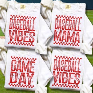 K&ouml;nnte beinhalten: Vier wei&szlig;e Langarmshirts mit rotem Text und einem karierten Rand. Die Shirts tragen die Aufschrift "Baseball Vibes", "Baseball Mama", "Game Day" und "Baseball Vibes". Die Shirts sind gefaltet und &uuml;bereinander gestapelt.