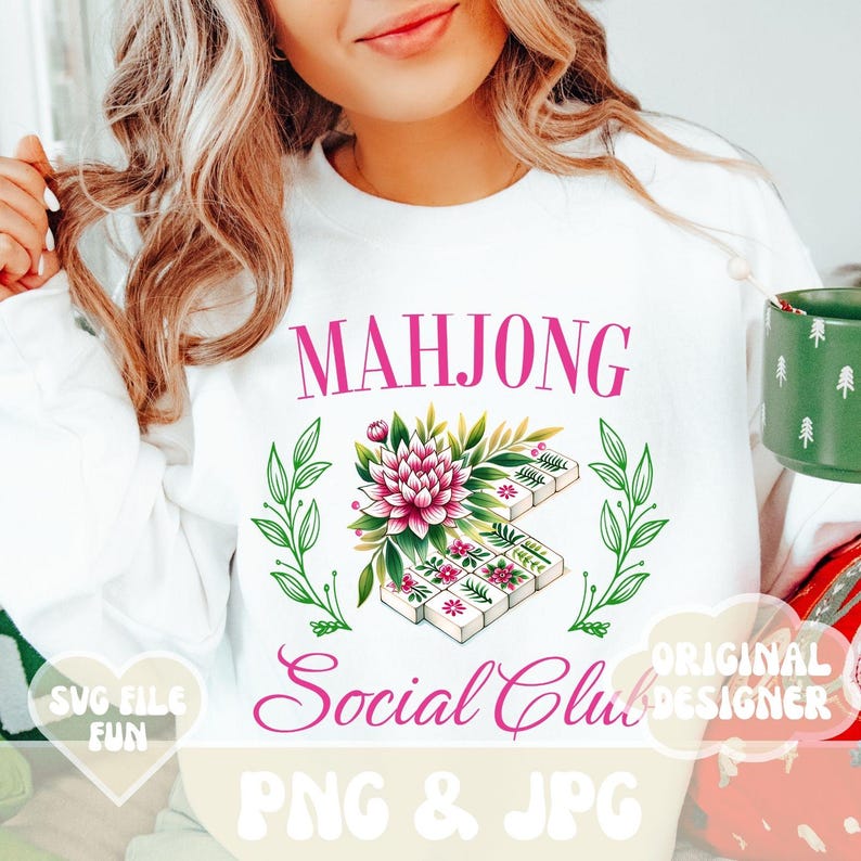 Puede incluir: Una sudadera blanca con un dise&ntilde;o floral rosa y el texto "Mahjong Social Club" en rosa. El dise&ntilde;o incluye una flor y fichas de mahjong. El texto "SVG File Fun" est&aacute; en un coraz&oacute;n rosa y el texto "Original Designer" est&aacute; en rosa.