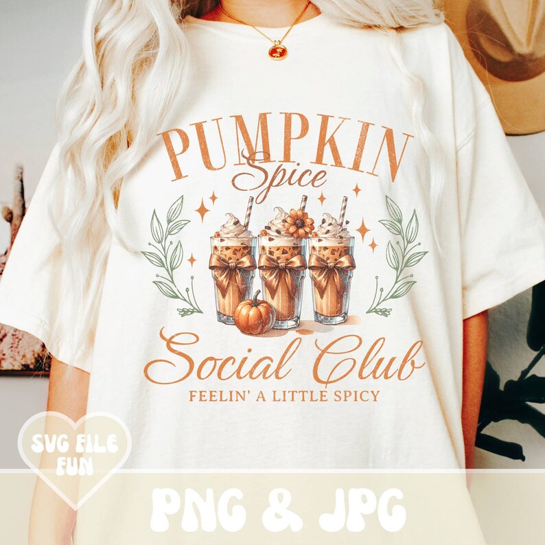 May include: Cream-colored t-shirt with a fall-themed graphic. The design features the text "PUMPKIN Spice Social Club" with illustrations of pumpkin spice lattes and a small pumpkin. The shirt also includes the text "FEELIN' A LITTLE SPICY".