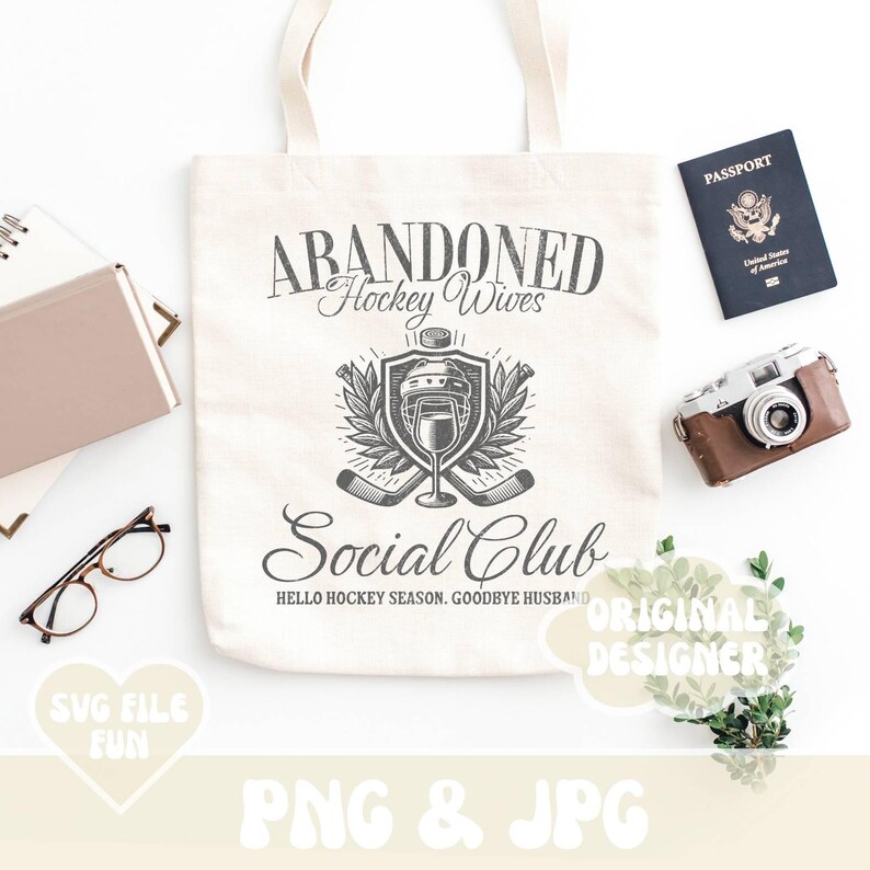 May include: A white tote bag with the text "ABANDONED Hockey Wives Social Club HELLO HOCKEY SEASON. GOODBYE HUSBAND" printed on it. The bag features a black and white illustration of a hockey helmet and sticks.