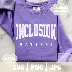 May include: Purple sweatshirt with the text "INCLUSION MATTERS" in white. The sweatshirt is a blank canvas for a design.
