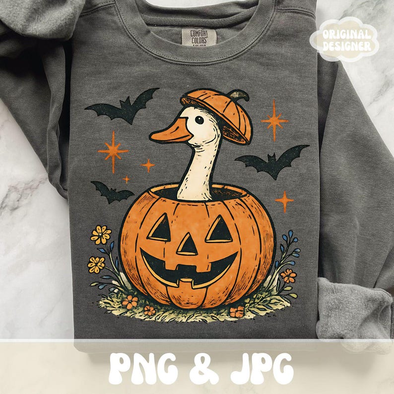 May include: Dark gray sweatshirt with a Halloween-themed graphic. The design features a white duck wearing a pumpkin hat, emerging from an orange jack-o'-lantern. Bats, stars, and flowers surround the pumpkin. The text "PNG & JPG" is at the bottom.