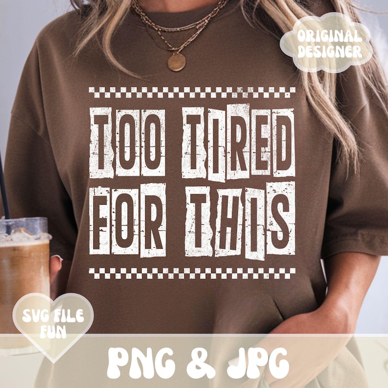 以下が含まれることがあります： 白い文字で「Too Tired For This」と書かれた茶色のスウェットシャツ。文字は、白いチェック柄の枠で囲まれています。