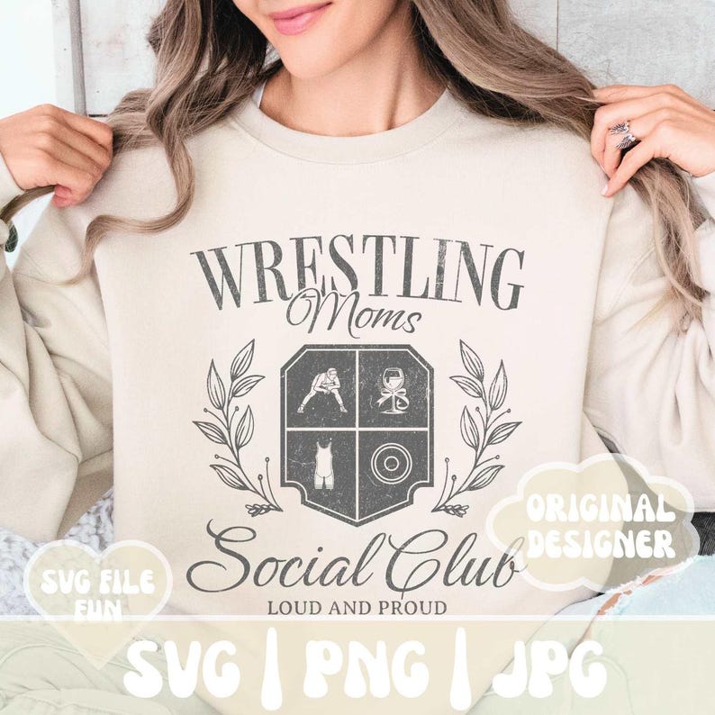 May include: A beige sweatshirt with a vintage-style graphic design that says "Wrestling Moms Social Club Loud and Proud". The graphic features a crest with wrestling-related imagery, including a wrestler, a weight, and a wrestling singlet.